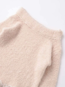 Close-up of fluffy apricot knit fabric with white lace trim detail on the hemline