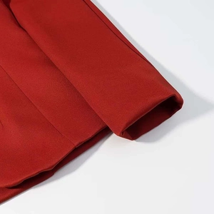 Detailed macro view of the tailored red suit sleeve cuff with clean stitching and texture