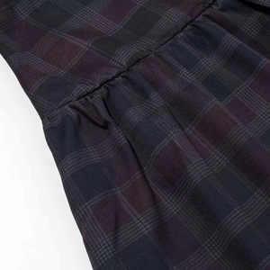 Detalle de los pliegues y textura de la tela en el conjunto de camisa y falda de cuadros