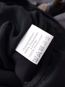 Macro shot of black V-neck bodysuit care label showing 100% polyester fabric details