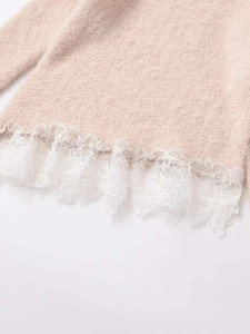 Detailed close-up of beige knitted sweater hem with delicate white floral lace trim
