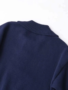 Detailed close-up of navy blue knit sweater featuring ribbed texture and large collar