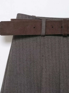 Detailed view of herringbone fabric texture and brown suede belt on high waist shorts