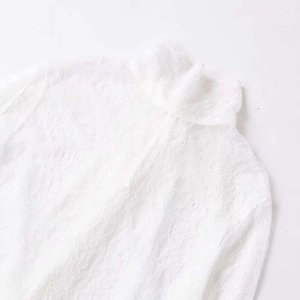 Haut élégant en dentelle florale blanche avec col montant et manches évasées