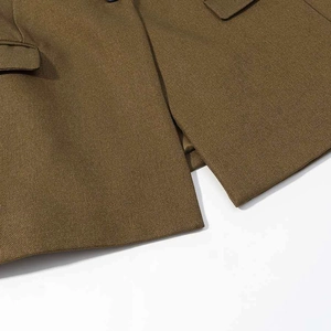 Detailed macro view of the hem and symmetrical flap pocket on this brown twill blazer coat