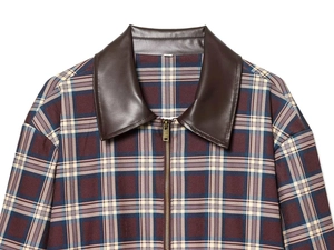 Détail de la veste vintage à carreaux avec col en cuir marron et fermeture éclair en métal