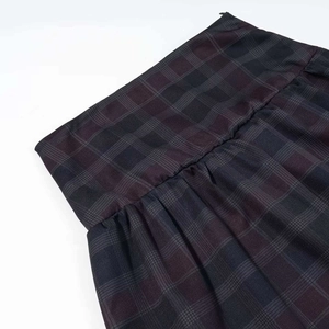 Detalle de cerca del estampado de cuadros vintage y la cintura plisada de la falda