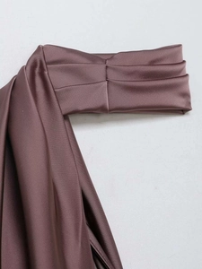 Close-up of the elegant draped pleats and glossy satin fabric of the brown halter top