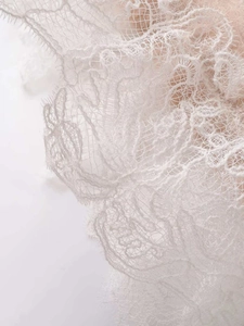 Close-up detail of white floral lace embroidery on loose-fit knit sweater for women