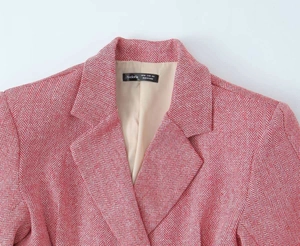 Dettaglio della trama a spina di pesce rosa e rever sul blazer doppiopetto