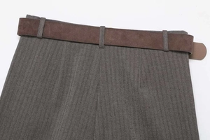 Detail of grey herringbone fabric texture and brown matte belt on tailored trousers