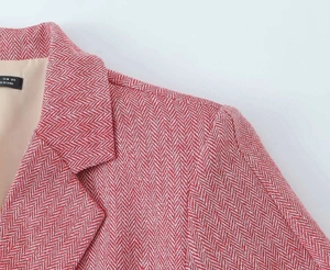 Dettaglio del colletto del blazer rosa a spina di pesce con etichetta della taglia tessuta
