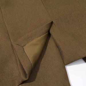 Detail of tan blazer with twill texture showing split hem and silk lining stitching