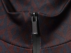 Detail of metal zipper on high collar dark red and black geometric pattern jumpsuit fabric