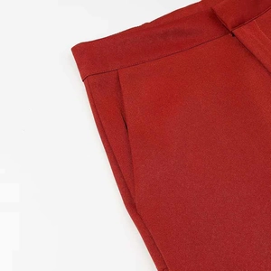 Detailed close-up of dark red suit trousers featuring waist stitching and fabric texture
