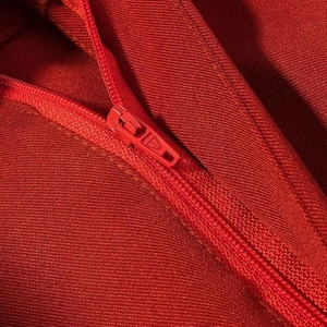Macro detail of high-quality red blazer zipper with textured twill fabric and sleek hardware