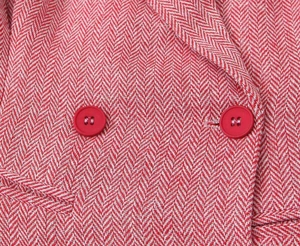 Macro di tessuto rosa a spina di pesce e dettagli dei bottoni rossi a doppiopetto