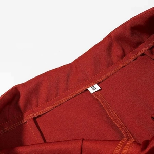 Macro detail of red woven fabric waistline showing neat stitching and fine texture