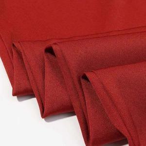 Close-up of deep red fabric showing detailed twill weave texture and elegant folds