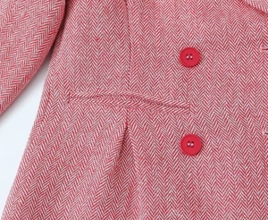 Dettaglio in primo piano della texture tweed rosa a spina di pesce con bottoni e tasca