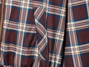 Gros plan du tissu écossais rouge et bleu de la veste avec poche latérale et zip métallique