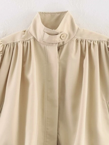 Detail of light khaki jacket with stand collar buckle and pleated shoulder design