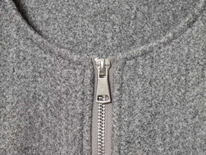 Close-up of the silver metal zipper and soft grey wool fabric on a bomber jacket