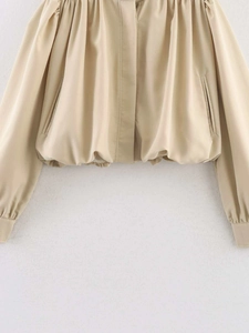 Detail of a beige cropped jacket showing gathered elastic hem and side pockets
