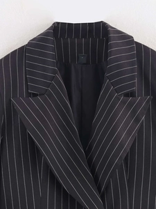 Close-up detail of peak lapel and fine white pinstripe texture on a black blazer jacket