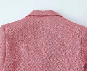 Dettaglio della trama tweed rosa a spina di pesce e del bavero sul blazer doppiopetto