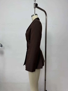 Detail view showing structured dark brown blazer side profile with unique peplum waist pleats