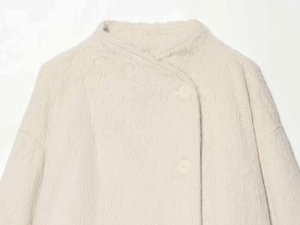 Detail view of plush beige faux fur jacket showing the collar and large button closure