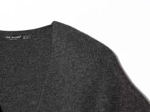 Close-up of the V-neckline and woven brand label on a dark grey knit sweater set
