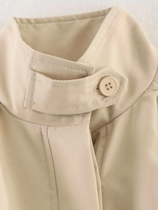 Close-up of khaki pleated jacket stand collar with adjustable strap and matte button