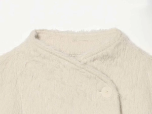 Detail of cream white plush jacket showing round neck with large matching button closure