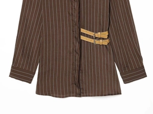 Detail view of brown striped shirt featuring decorative leather side buckles with silver rings
