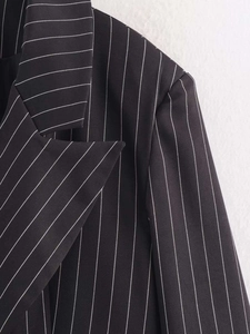 Detail shot of black pinstripe blazer showing structured lapel and shoulder fabric texture