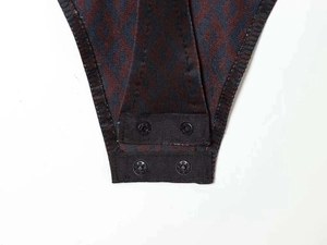 Detail view of functional snap button closure on dark geometric knit bodysuit