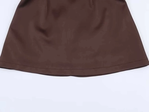 Detail view of the deep brown dress hem showing precise double-needle stitching work