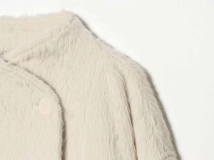 Detail of soft beige faux fur jacket showing plush texture and minimalist button