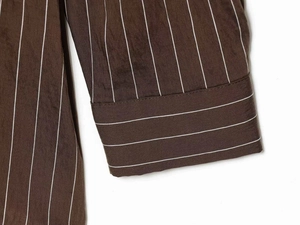 Detailed close-up of brown striped shirt cuff showing fine stitching and fabric texture