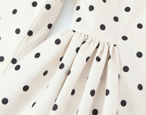 Detailed view of cream polka dot fabric with elegant ruffled pleats and smooth texture