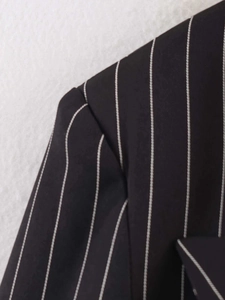 Close-up of shoulder seam and white pinstripe detail on black minimalist blazer