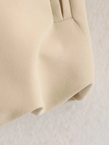 Detailed close-up showing the pleated design and woven texture of the khaki jacket