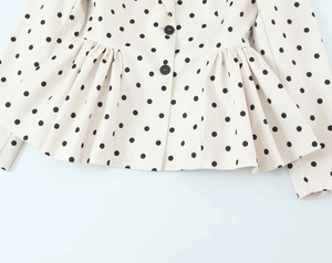 Detailed view of cream peplum blazer with black polka dots and button closure