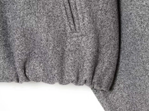 Detail of grey bomber jacket showing elastic hem and soft textured wool fabric