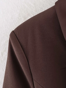 Detailed macro shot of dark coffee blazer shoulder stitching and smooth satin-like fabric