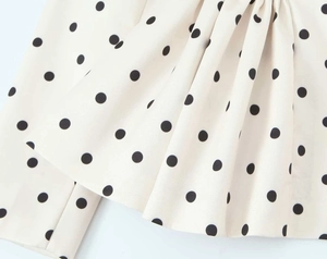 Detailed macro view of white chiffon fabric with black polka dots and pleated texture