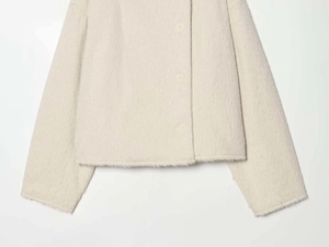 Detail of soft cream faux fur texture on the stylish long-sleeved double-breasted jacket