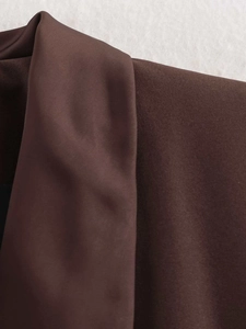 Detail shot of a dark brown satin lapel collar on a tailored blazer with fine stitching